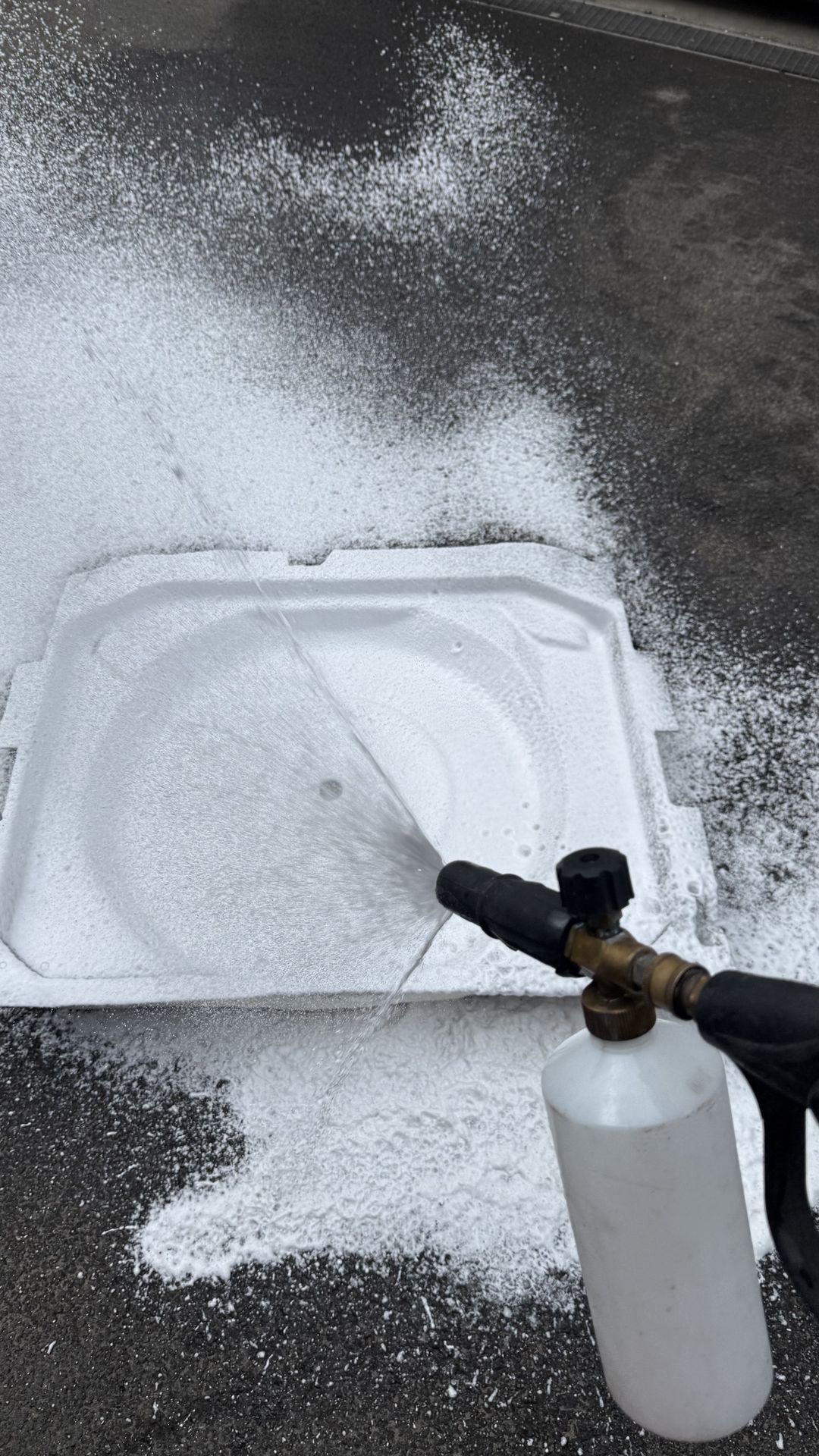 Nettoyage en profondeur avec canon à mousse d’une garniture démontée du coffre d’un Peugeot 3008 après le renversement d’un bidon d’huile.